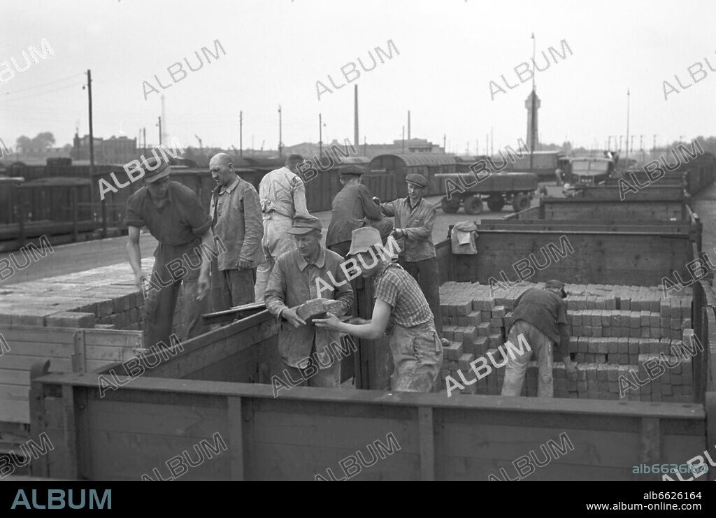 Workers loading bricks from a rail wagon on the back of a truck, for the further transport for the reconstruction of the destroyed city of Berlin. 1949