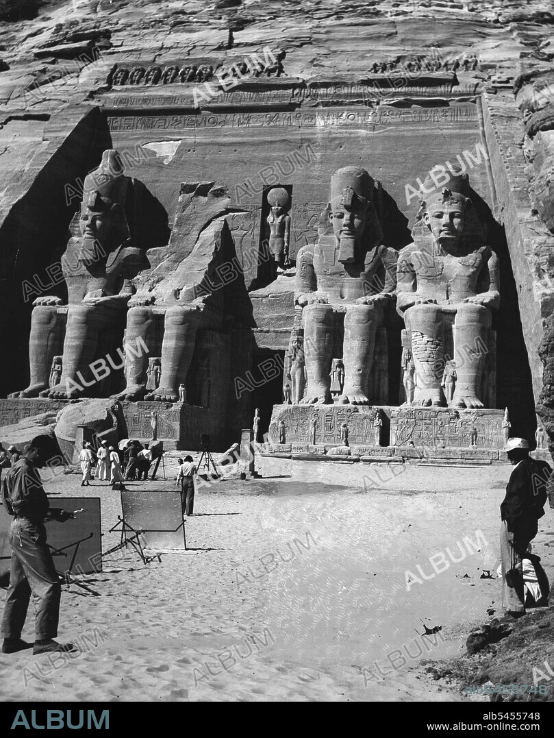 Filming An Ancient Scene -- M-G-M's "Valley of the Kings" unit, which spent more than two months in Egypt filming scenes for the spectacular adventure story, photographs the great Abu Simbel temple, which was carved more than 4,000 years ago out of a mountain of solid rock. Robert Taylor and Eleanor Parker travelled more than 35,000 miles with the company while filming scenes for the picture. Robert Pirosh directed. The huge temple at Abu Simbel, with its colossi hewn out of rock. July 03, 1954. (Photo by Saturday Magazine).