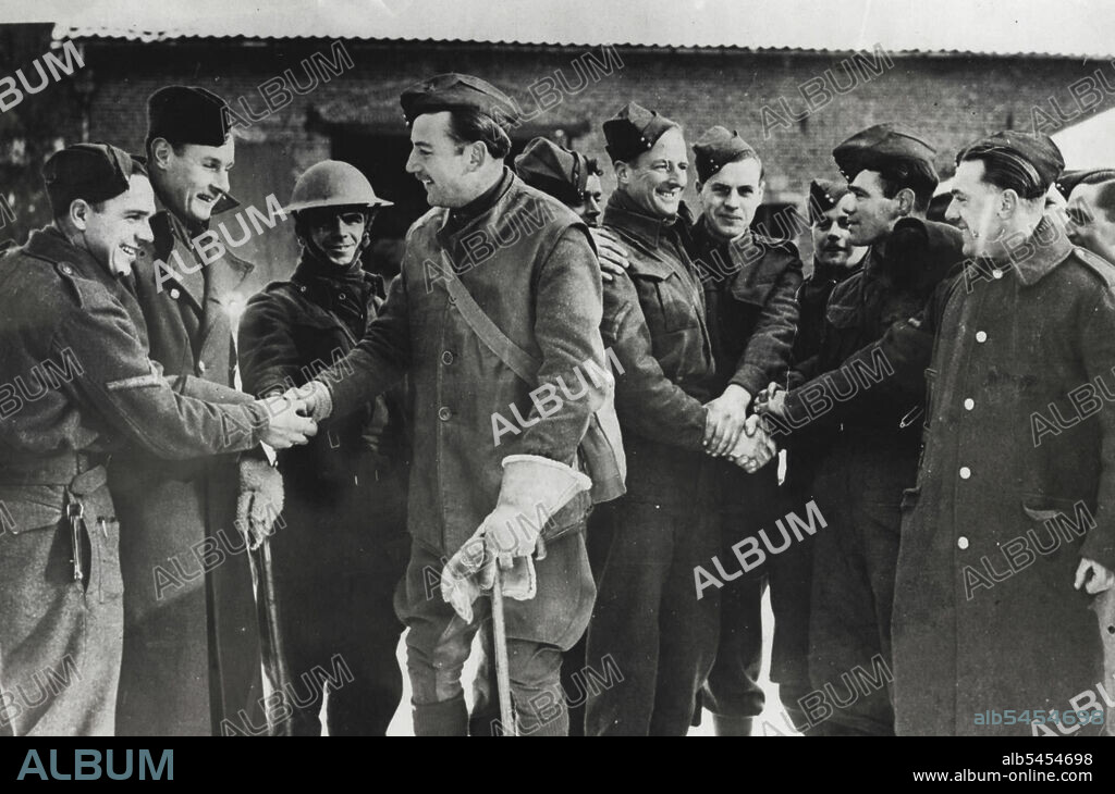 First Army Decorations Of The War -- Captain Francis Peter Barclay (centre, holding stick) and Lance-Corporal Herbert Arthur Davis (almost behind him) receiving congratulations. Captain P. F. Barclay was awarded the Military Cross and Lance Corporal H. Davis the Military Medal. Both men belong to the Norfolk Regiment and their decorations were given for conspicuous gallantry and coolness on night patrol. Captain Barclay led his patrol far into the enemy lines and secured a house and then continues the reconnaissance. On their return they were fired at by the enemy and took cover in a ditch, but being without ammunition they withdrew without loss to our lines. March 25, 1940. (Photo by British Official Photograph).