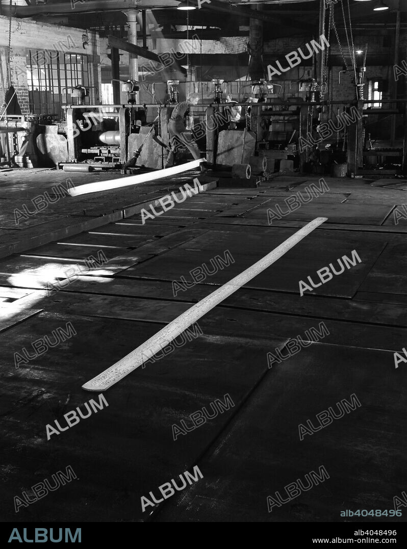 Rolling steel, J Beardshaw & Sons, Sheffield, South Yorkshire, 1963. The process of rolling steel involves running the steel bar through rollers to produce, in this case, a thinner steel bar.