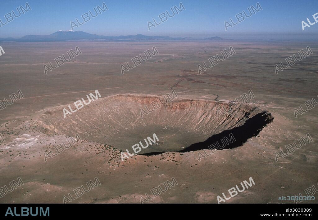 Aerial view of Meteor Crater, Arizona. Sometimes called the Barringer Crater, after the mining engineer who first suggested that it was formed by a meteor impact. It is believed to be about 50,000 years old. The crater is in northeastern Arizona, near Winslow, and is about 200 meters (600 feet) deep and 800 meters (1/2 mile) across. Several attempts to mine the iron-rich material of the meteor were made before a visitor center was built in the 1960's. Two new minerals - coesite and stishovite - were identified here; both are high-pressure forms of silica. In recent years the crater has been used for astronaut training & studies in planet comparison.