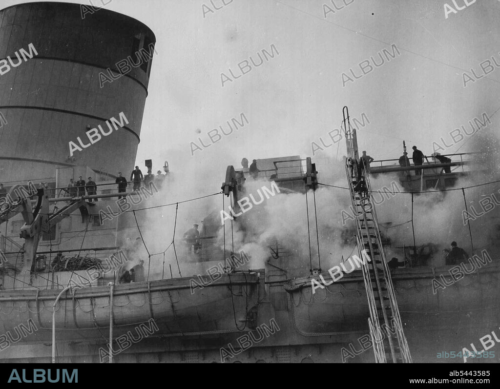 Mystery Fire In Queen Elizabeth -- Firemen and dock hands are seen fighting the blaze on board the Queen Elizabeth, today March 8, which broke out in the bedding store of the isolation hospital on the Port side of the promenade deck. A Mystery fire broke out in the world's largest liner - The Queen Elizabeth, in dock at Southampton, today March 8. Police assisted by Cunard White Star officials are probing the mystery of the outbreak, which luckily confined to the isolation hospital. It has been officially stated that the damage to the £6,000,000 liner is slight. March 08, 1946. (Photo by Associated Press Photo).