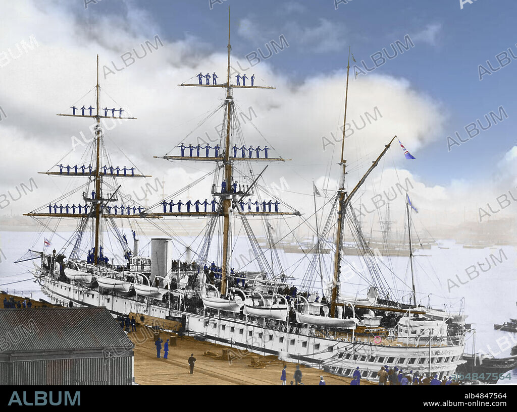 Negative circa 1900, Victorian era. HMS Jumna in 1880, a Euphrates-class troopship launched at Palmers Shipbuilding and Iron Company in Hebburn on 24 September 1866. The shipâ€™s company are manning the rigging as the Royal Yacht Victoria and Albert comes a.