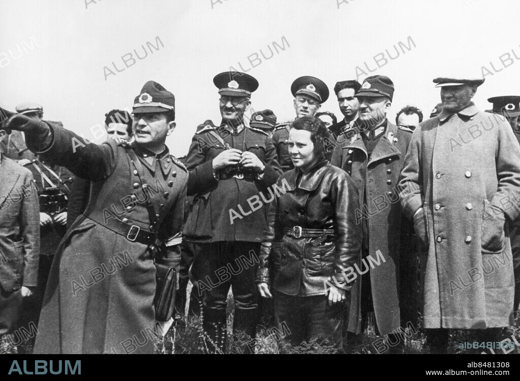 Orig. bildtext... UNE AVIATRICE DANS L'ARMEE TURQUE. L'aviatrice Sabiha, fille adoptive de Mustapha Kemal Ataturk, fait partie depuis deux semaines de l'armée de l'air turque. Pendant la dernière révolte des tribus kurdes, elle a participé aux bombardements aeriens et a été décorée par le Président du Conseil, M. Ismet Inonu. L'aviatrice Sabiha pendant les manoeuvres qui se déroulent actuellement en Turquie. A dr. M. Mustapha Kemal Ataturk. 211037 Anm. S Gökvßen, 1913-2001, Turkiets första kvinnliga flygare och den första kvinnliga stridspiloten i världen; ett av Mustafa Kemal Ataturks åtta adoptivbarn. M K Atatürk, 1881-1938, turkisk premiärminister 1920-1921, republiken Turkiets grundare och första president 1923-1938. Militärer Flygare Skinnjackor Rockar Far och dotter Peka Visa Handen i fickan CD520 persons: MUSTAFA KEMAL ATATURK;SABIHA GÖKCEN sites: TURKIET.