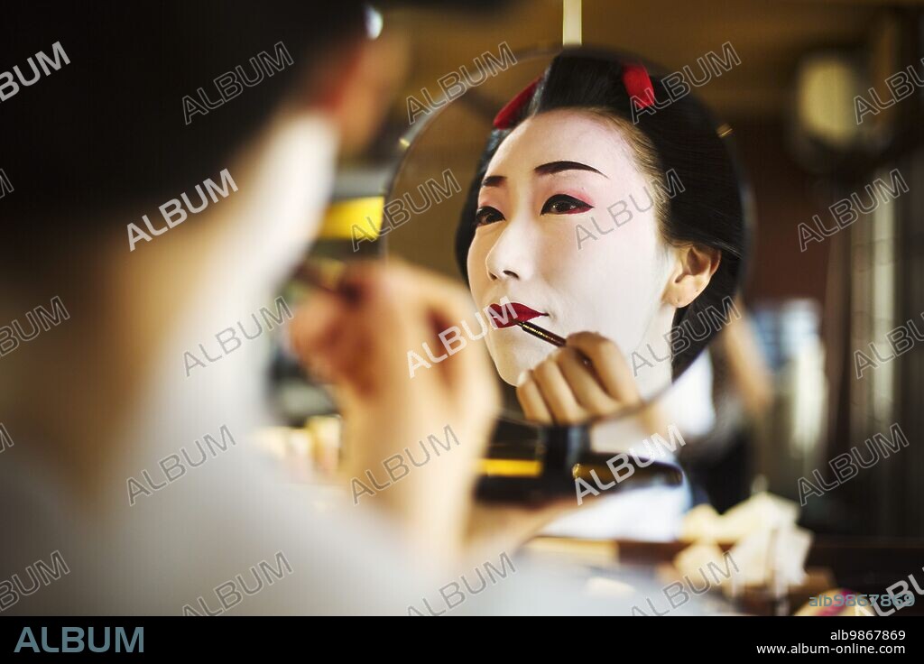 A modern geisha or maiko woman being prepared in traditional fashion, with white face makeup. || Model released / Mininum fee EUR 20. 28/07/2016
