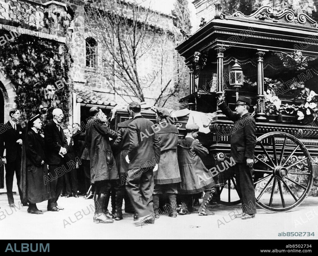 ITALIEN ROM 1930-04.. Orig. bildtext... BODY OF THE QUEEN OF SWEDEN LEAVES ROME. 12.4.30. The coffin containing the body of the Queen of Sweden, who died at her villa in Rome, recently left Swinemund, on a Swedish Battleship, for Stockholm, where the funeral takes place on 12th. April. O.P.S. The coffin containing the body of the Queen of Sweden leaving the Villa Swede in Rome, for conveyance to Swinemund for Stockholm. The cortege is being saluted by Fascists. Orig. bildtext... DIE HEIMKEHR DER TOTEN SCHWEDENKÖNIGIN. U.Bz. König Gustav von Schweden und sein Sohn wohnen der Ueberführung der verstorbenen Königin Viktoria aus der Villa Schweden in Rom zum Bahnhof bei. Orig. bildtext... KISTAN BÄRES UT UR VILLA SVEZIA. Anm. Victoria, 1862-1930, svensk drottning från 1907, gift med Gustaf V och fick med honom sönerna Gustaf (VI) Adolf, Wilhelm och Erik. P.g.a. sviktande hälsa framlevde hon sina sista år i Rom, där hon avled. Gustaf V, 1858-1950, Sveriges kung från 1907, son till Oscar II och drottning Sofia. Hjul Ekrar Droskor Vagnar Kistor Kungligheter Korteger Profiler Bärare Stövlar Fascisthälsning CD535 persons: VICTORIA, DROTTNING AV SVERIGE*;WILHELM, PRINS AV SVERIGE;GUSTAF V, KUNG AV SVERIGE sites: SVERIGE*;ROM;ITALIEN.