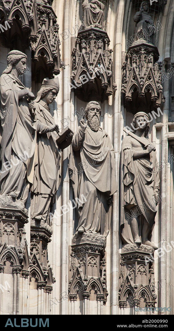 Germany, Cologne, Cologne Cathedral, South Facade, Right Portal, Portal of Gereon, Jamb Sculpture. Cologne Cathedral was built was built to house the relics of the Three Magi, under the direction of Archbishop Conrad von Hochstaden. Construction of the present Gothic church began in August 15th, 1248 and completed in 1880. In 1996, the cathedral was added to the UNESCO world heritage list of culturally important sites. Seen are the jambs sculptures of saints to the left of the portal of Gereon. It was destroyed in world war II and rebuilt in 20th century. Seen are the portal of Gereon jamb sculptures, depicting saints who were active or are venerated in Cologne or in the Rhineland.