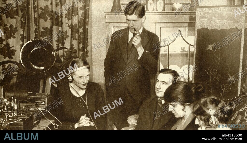 A family listening to the results of the general election of 1923, (1935). 'Wireless brought the election results into the homes of the people, enabling them to get the very latest results in the privacy and comfort of their own fireside.' From "The Silver Jubilee Book - The Story of 25 Eventful Years in Pictures". [Odhams Press Ltd., London, 1935].