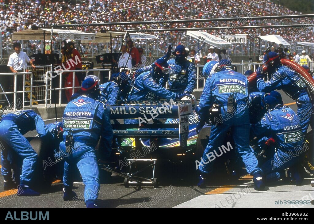Pit stop for Michael Schumacher's Benetton-Ford, 1994. Mechanics swarm around the car at a stop to refuel and change tyres during a Grand Prix in Schumacher's first championship-winning season.