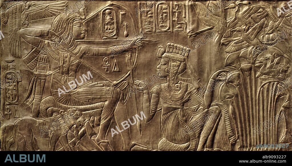 Details of the exterior of the gilt shrine. The Queen helps the King in a ritual hunting scene. Tukankhamen, by Christiane Desroches Noblecourt, page 41..  The external walls and the doors of the shrine are subdivided into panels framed by hieroglyphic inscriptions with scenes showing Tutankhamun and his wife in various aspects of married life, a theme that recalls the scenes of the Amarna Period. The entire decorative scheme of the shrine has strong symbolic connotations associated with the religious and political spheres. The intimate ties between the pharaoh and his bride represent the serene relationship between god and man. For this reason it is almost always the queen who is the active figure, embodying the concept of humanity paying homage to the celestial, personified by Tutankhamun.  The couple are adorned with jewels and dressed in finely pleated, adherent clothing. The left wall is divided into four panels. The hunting scene is to be interpreted as a symbolic episode referring to the pharaoh's role in the maintenance of the cosmic order and his constant fight against chaos (symbolized by the birds in the swamp).