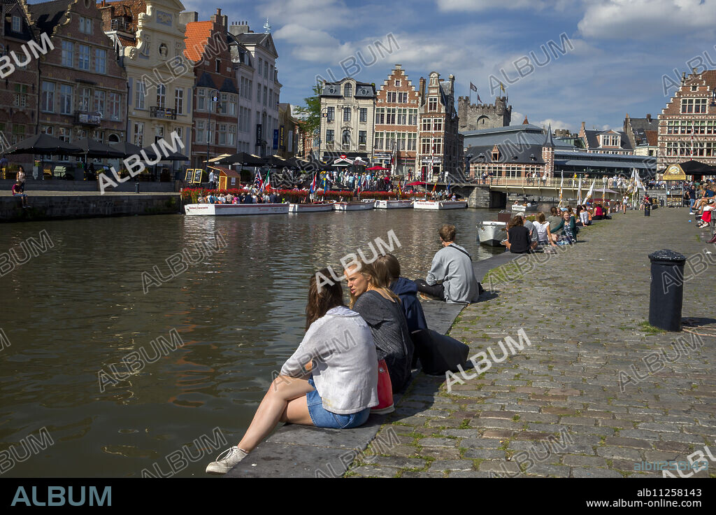 Young people enjoy summer sunshine along the Graslei and Korenlei, Ghent, Belgium, Europe.