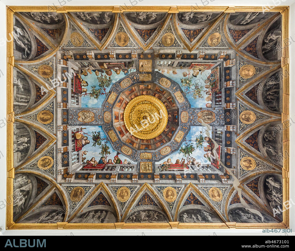 Ferrara, Palazzo Costabili or Palazzo di Ludovico il Moro (today it is the seat of the National Archaeological of Spina), Aula Costabiliana o Hall of the Treasure, vault: XVI century frescoes by Benvenuto Tisi, known as il Garofalo.. Along the sides of the ceiling a large balcony, where Oriental rugs are hanging out, is painted. There is a gallery of characters, many of them have musical instruments. They leanfrom the balcony and show the observers their love for arts, music and poetry. The ceiling is almost a showcase of the aristocracy of the time with portraits of rare elegance. In an evocative scenography, above the balcony, there are a turquoise sky , with a gazebo filled with branches of fruit, knotted around the balustrade. This room is, in fact, a hortus conclusus, a secret garden realised by the owner for his notable guests.. At the centre there are a magnificent rose window in carved and gilded wood, and a painted architecture that is used both as a decoration and as a cover. All around runs a frieze that goes all around the room, with grotesque medallions depicting with scenes taken from mythology and stories of ancient Rome.