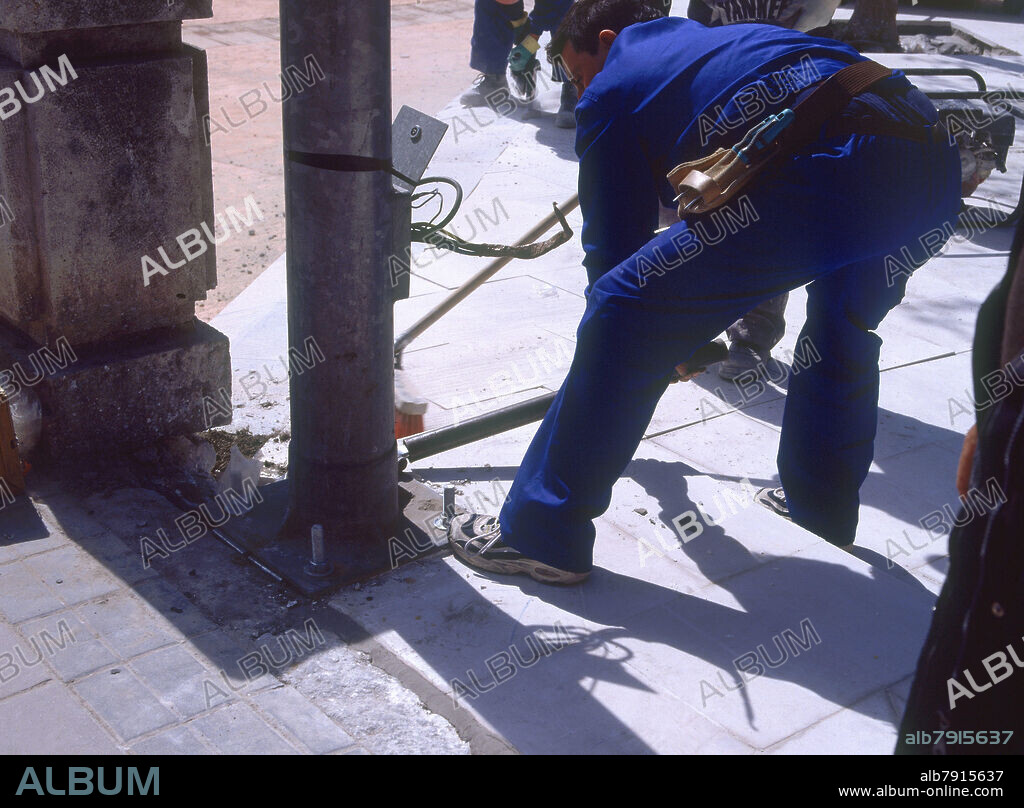 OBRERO ATORNILLANDO UNA FAROLA.