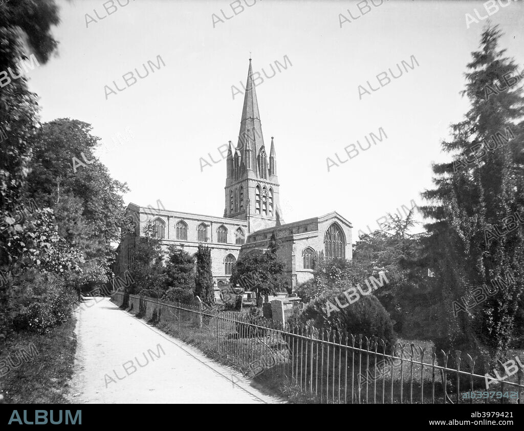 Exterior of the 12th-13th century St Mary's Church, Cogges, Witney, Oxfordshire, 1883. Viewed from the south west, showing the large central tower with octagonal spire and clerestory windows.