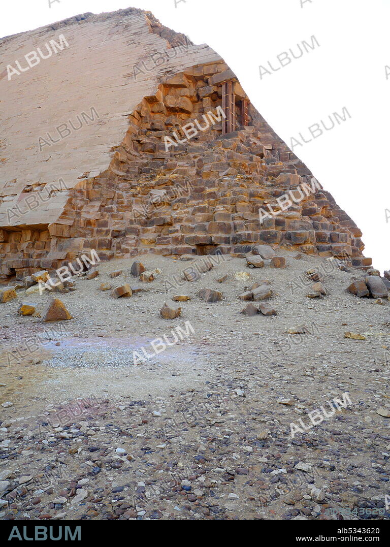 The Bent Pyramid is an ancient Egyptian pyramid located at the royal necropolis of Dahshur, approximately 40 kilometres south of Cairo, built under the Old Kingdom Pharaoh Sneferu (c. 2600 BC). A unique example of early pyramid development in Egypt, this was the second pyramid built by Sneferu. The Bent Pyramid rises from the desert at a 54-degree inclination, but the top section (above 47 meters) is built at the shallower angle of 43 degrees, lending the pyramid its very obvious 'bent' appearance..