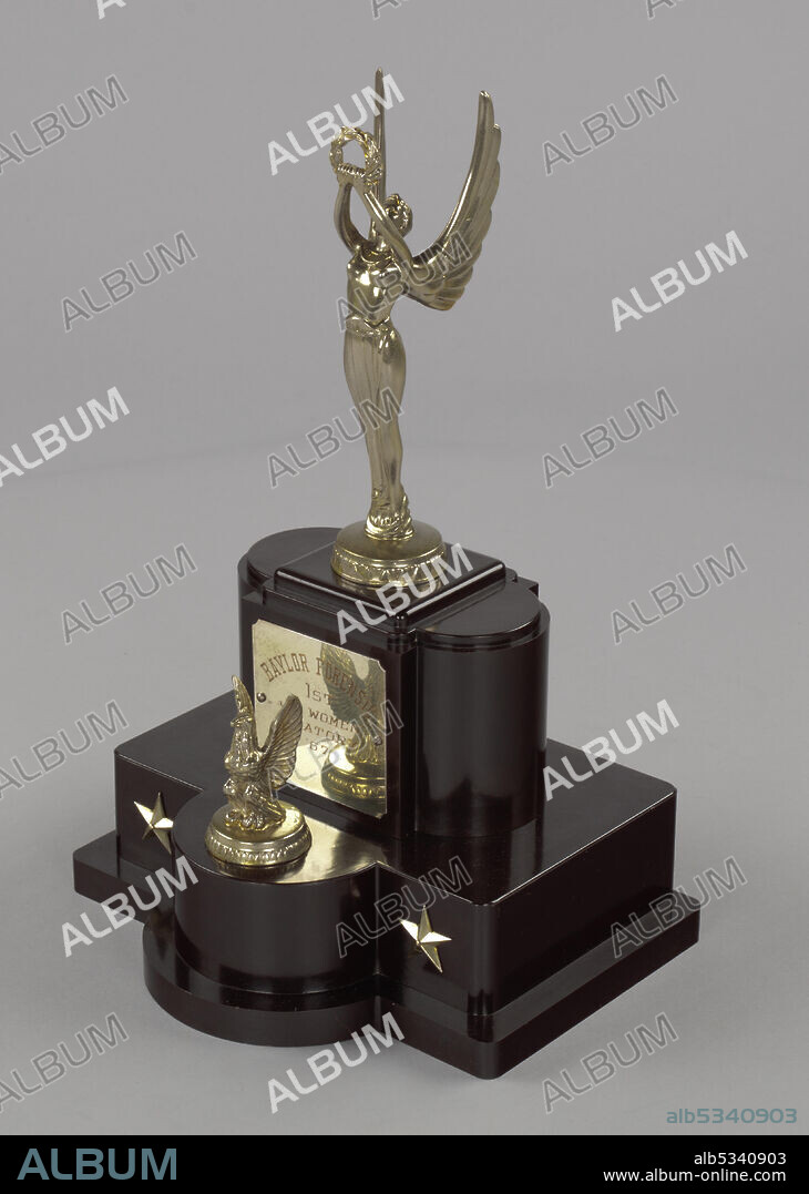 A. C. REHBERGER COMPANY. Texas Southern University in Houston, Texas, is a public historically black university (HBCU). The debate trophy has a dark brown plastic base with metal shapes featured as decoration. The top of the trophy features a female statuette with wings holding a wreath above her head with both hands. The base has five staggered levels in varying shapes which taper off to form the podium where the metal figurine stands. There is a metal plaque on the level below the statuette which reads, [BAYLOR FORENSIC/JR WOMEN/ORATORY/'67]. In front of the plaque is a small metal eagle figure. A level below and to the right and left of the eagle are metal stars. The trophy base is hollow, with a manufacturer's mark on the hollow inside. The manufacturer's mark reads, [A. C. REHBERGER CO./TROPHIES/REH/CRAFT/AWARDS/CHICAGO 14, ILL.].