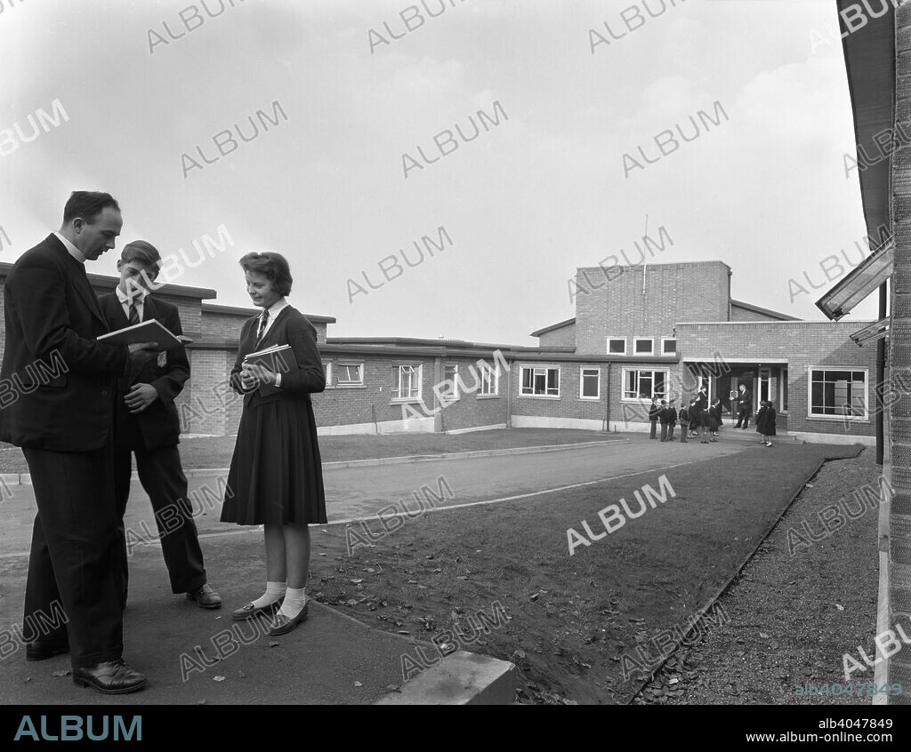 Pope Pius X school, Wath-upon-Dearne, Rotherham, South Yorkshire, 1959. The school opened in 1959. In 2007 it was awarded special status as a humanities college. In the photograph, the local Father speaks with pupils outside the school.