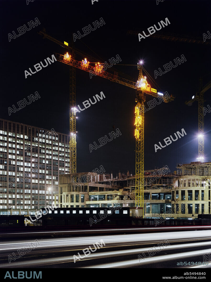 JOHN LAING PLC. Vauxhall Cross, Albert Embankment, Vauxhall, Lambeth, London, 03/12/1990. A night-time view looking east from Vauxhall Bridge during the construction of Vauxhall Cross, showing one of the cranes on site bedecked with illuminated Christmas decorations. Vauxhall Cross, also known as the SIS or MI6 Building, was designed by the architect Terry Farrell and was built by Laing Management Contracting for Regalian Properties. It was sold to the government, becoming the headquarter offices for the British Secret Intelligence Service or MI6. Laing won the contract for the building in 1989, with ground works starting in 1990 and completion of the structure taking place in 1992.