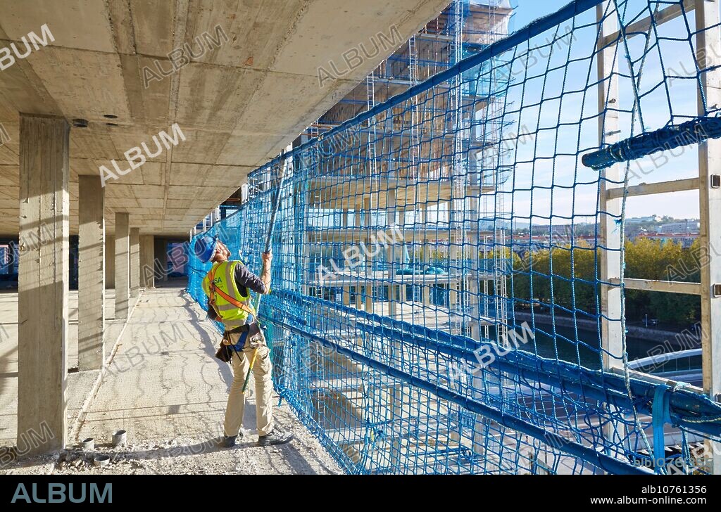 Worker placing Security System Work RESA. Protection in building work in construction. System that eliminates the possibility of people falling in the works. Homebuilding. Donostia, San Sebastian, Basque Country, Spain.