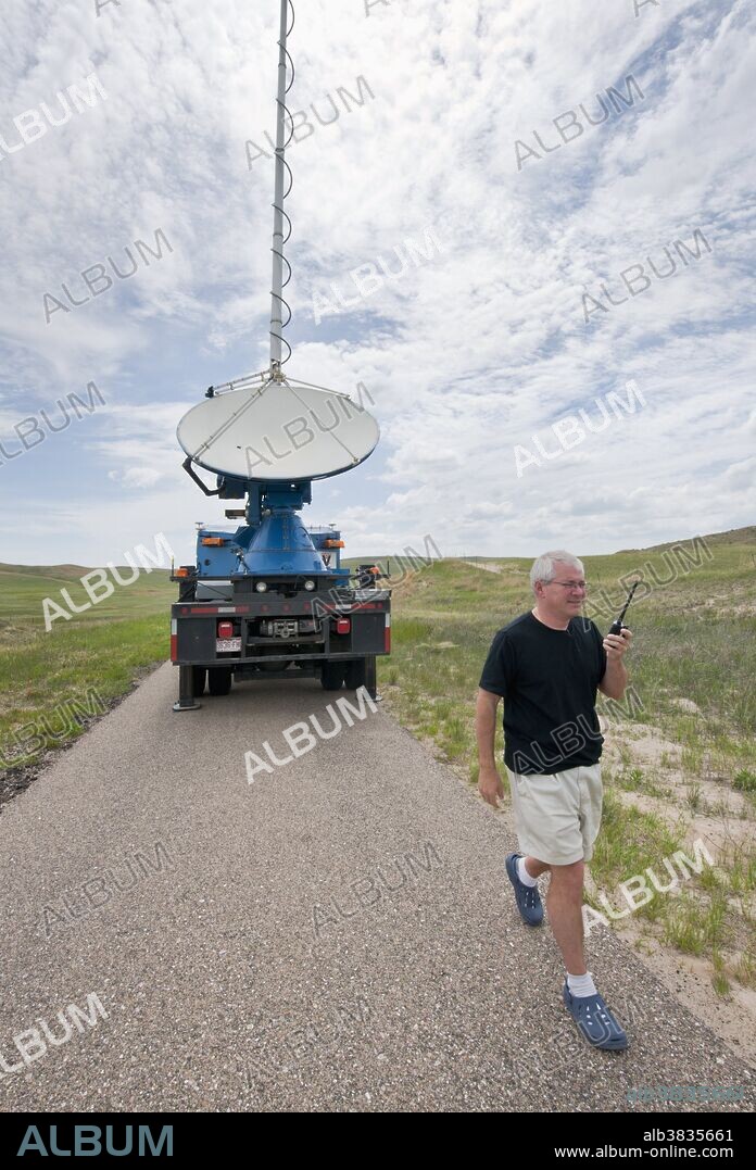 Scientist Joshua Wurman, inventor of the Doppler on Wheels portable weather radar truck (seen in background), uses a two-way radio to communicate with fellow VORTEX 2 tornado researchers in rural Nebraska on May 31, 2010.