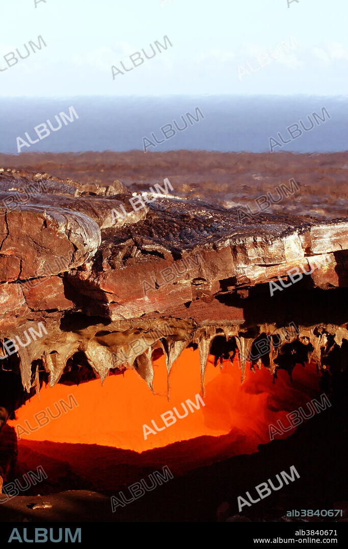 Lava tube skylight, in Kilauea Volcano, Hawaii. View into an active lava tube with a skylight. Lava tubes form when the surface of a lava flow cools and solidifies, while the interior remains molten. The molten lava then flows through a hollow passage of cooled rock. Here, part of the roof of the tube has collapsed, allowing a view into the tube.