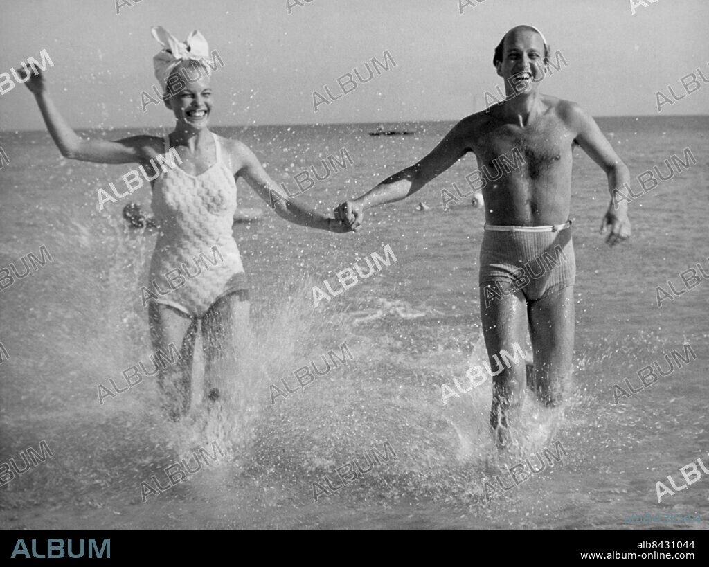 Orig. bildtext... FRÅN DET SOLIGA FALSTERBO. Black and white: Mary Rapp och Hasse Funck. Anm. H Funck, 1917-2004, operettsångare, balettdansör och regissör Se även XAD771 Baddräkter Hand i hand Springa Bildserier Fotoreportage CD306 persons: HANS HASSE FUNCK;MARY RAPP sites: SVERIGE;FALSTERBO.