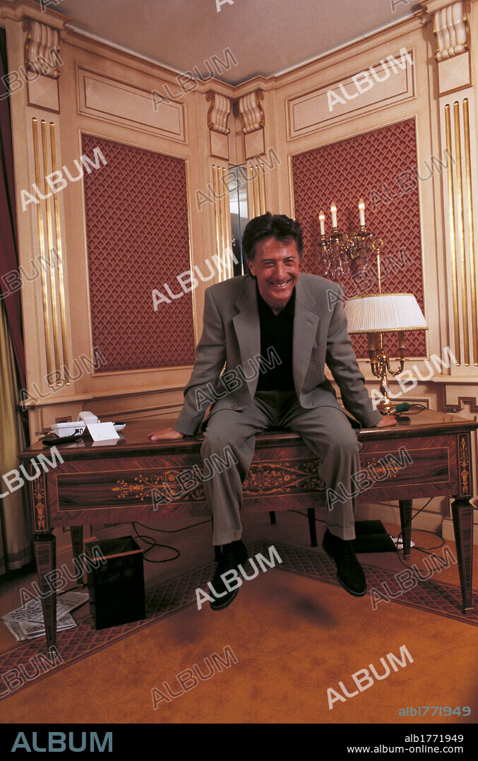 Artist Dustin Hoffman. Actor Dustin Hoffman, smiling, sitting upon a desk in a study. 1993.