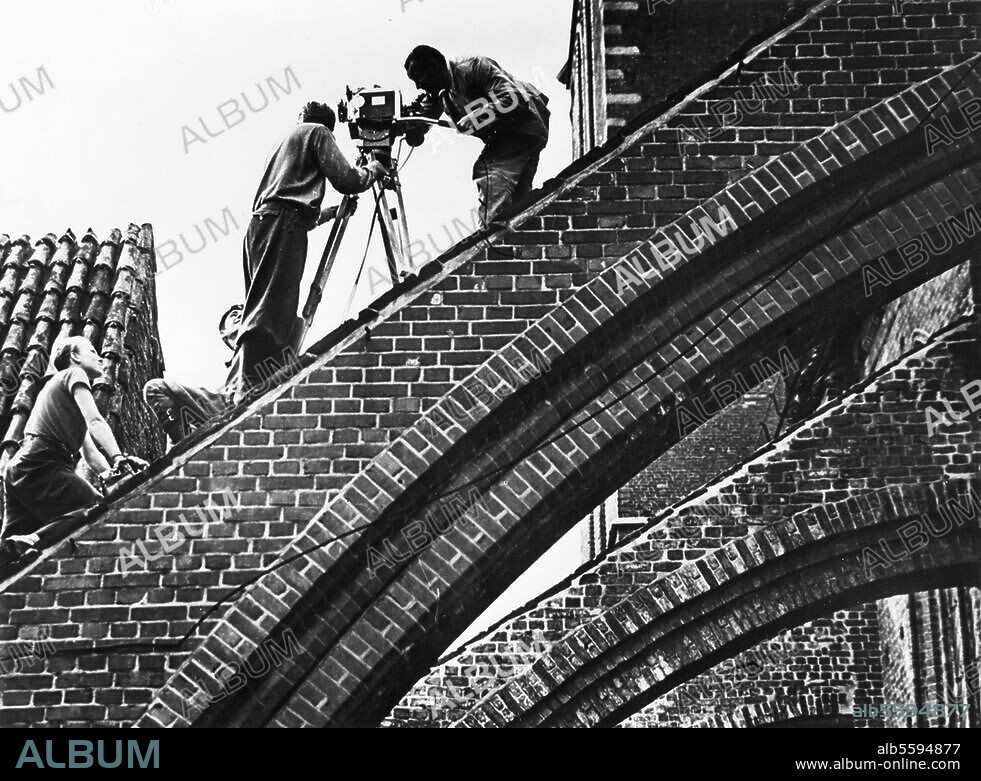 WALTER HEGE. Hege, Walter Fotograf 1893-1955.-Dreharbeiten zu dem Kulturfilm "Auf den Spuren der Hanse": Mit der Kamera auf einem Strebepfeiler der Marienkirche in Wismar.-Foto, um 1930.