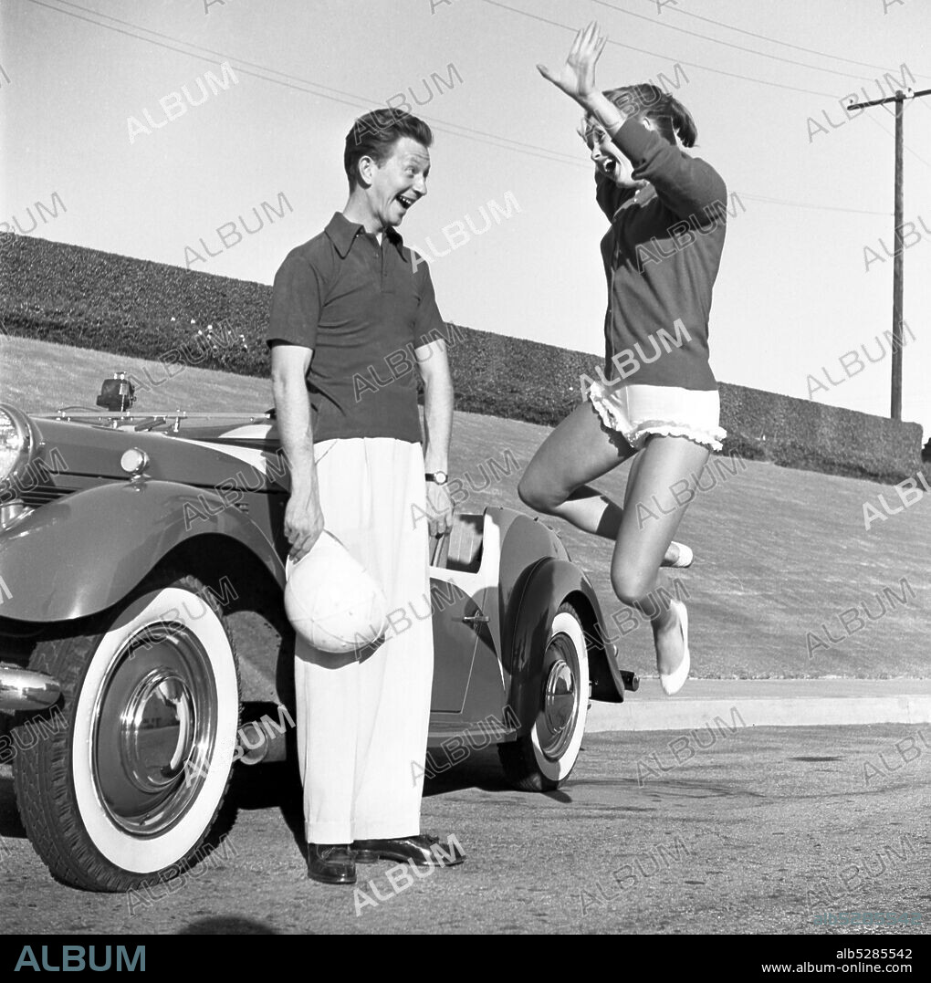 DONALD O'CONNOR. 1953, Los Angeles, California, USA: DEBBIE REYNOLDS jumps for joy as DONALD O'CONNOR stands beside his sports car.