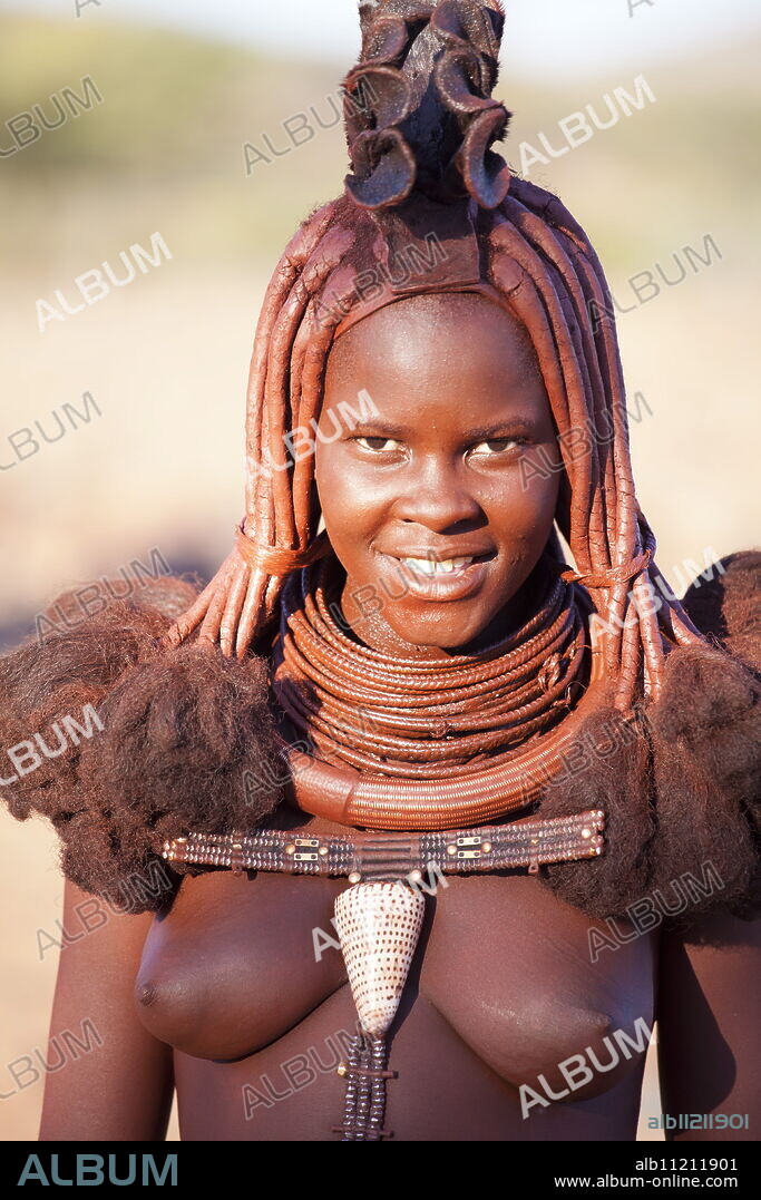 Young Himba woman wearing traditional dress and jewellery and with her skin covered in Otjize, a mixture of butterfat and ochre, Kunene Region, formerly Kaokoland, Namibia, Africa.