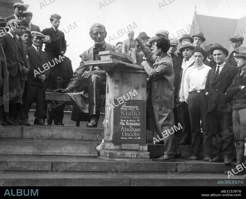 Newark, New Jersey:  November 11, 1924 Isamu Noguchi, 19 year old star pupil of the New Leonardo da Vince Art School in New York. Here he is modeling a miniature copy of the Lincoln Monument in Newark while passersby look on in wonder and admiration.