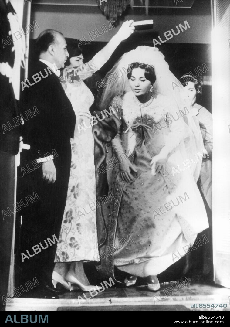 Orig. bildtext... THE SHAH MARRIES HIS ART STUDENT. There was great rejoicing in Teheran when the Shah of Persia married beautiful 21-year-old art student miss Farah Diba who thus became the Empress Farah of Persia. The ceremony took place in one of the most glittering rooms in the world, the hall of mirrors in the imperial palace in Teheran. This picture shows:- The beautiful bride stepping under the koran held by her mother as she set out for her marriage ceremony. On the left can be seen her uncle Mohammed Ali Ghotbi. Anm. F Diba, 1938-, gift med shahen av Iran från 1959 Brudar Brudklänningar Koranen Ceremonier Cd466 persons: FARAH DIBA;MOHAMMED ALI GHOTBI sites: TEHERAN;IRAN.