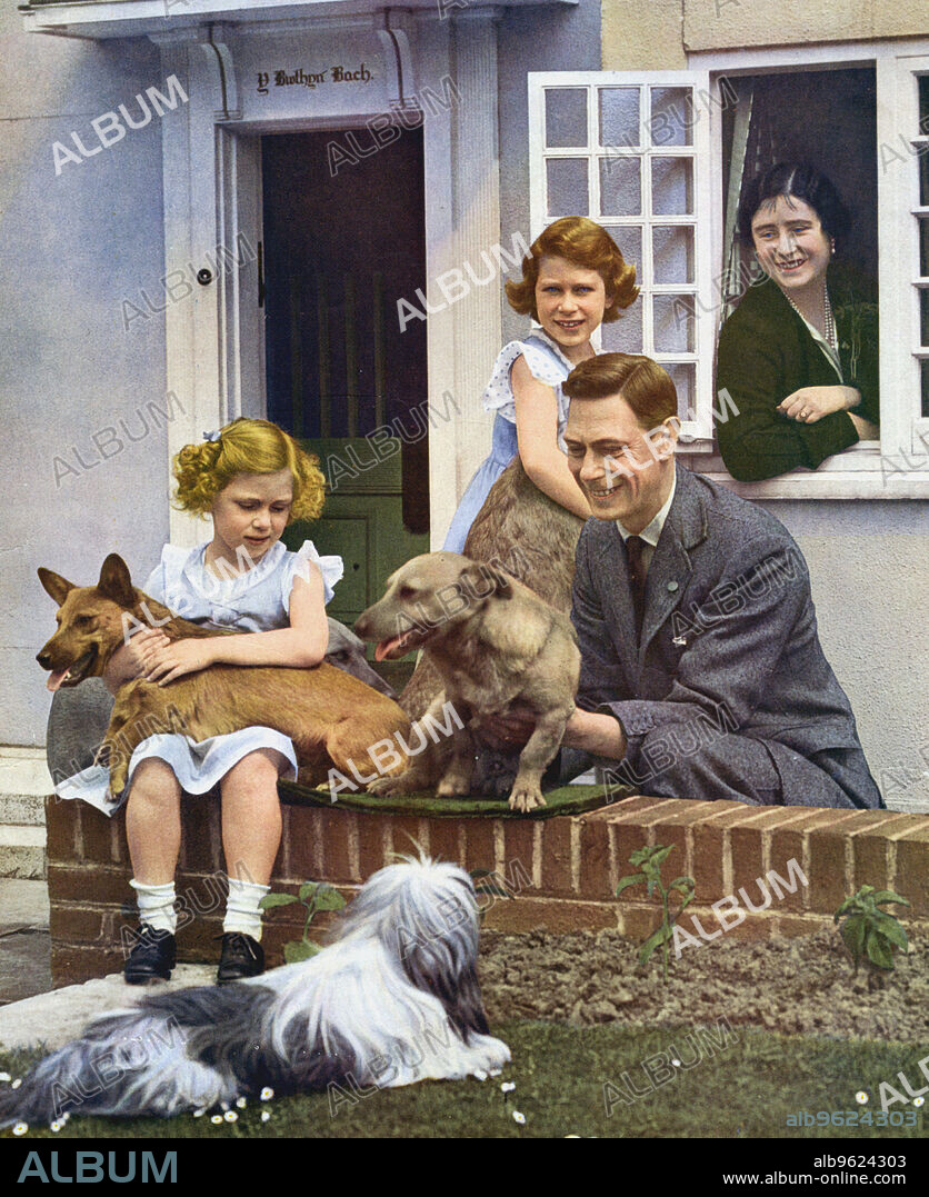 The Royal Family at Windsor, 1930s. King George VI with his daughters and their pet dogs outside Y Bwthyn Bach (The Little House), the gift of the Welsh people to Princess Elizabeth (standing by the window). Princess Margaret is seated on the wall with a dog on her lap and Queen Elizabeth looks on from inside the cottage.