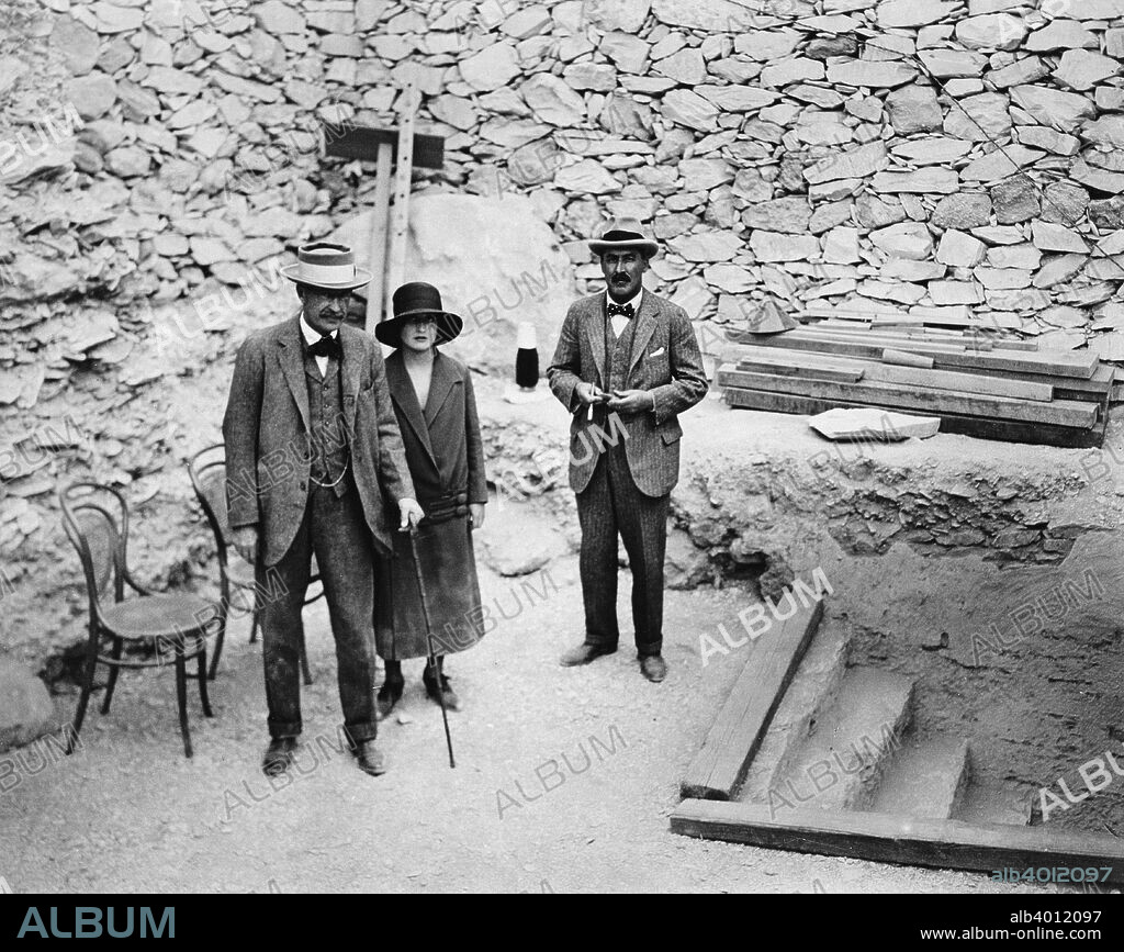 Lord Carnavon's first visit to the Valley of the Kings, Egypt, 1922. Lord Carnavon (1866-1923), his daughter Lady Evelyn Herbert, and archaeologist Howard Carter (1874-1939) at the entrance to the tomb of Tutankhamun. Lord Carnarvon was Carter's financial backer in his excavations in the Valley of the Kings. The discovery of Tutankhamun's tomb in 1922 was one of the most astounding discoveries in archaeology. Tutankhamun was a previously unknown pharaoh whose name had been eradicated from historical records by one of his successors because of his association with the heretical pharaoh Akhenaten, who was Tutankhamun's father-in-law. Consequently his tomb, uniquely, had remained undisturbed by grave robbers.