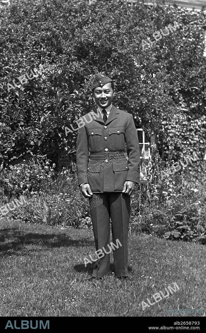 A man stood in the garden on a sunny day wearing his armed forces uniform. He is smartly dressed.