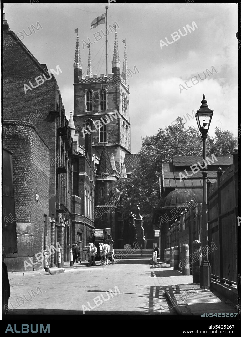 CHARLES WILLIAM PRICKETT. Southwark Cathedral, Montague Close, Southwark, Greater London Authority, 1930s. Looking east along Winchester Street towards the central tower of Southwark Cathedral, showing a horse-drawn cart on the road outside Borough Market to the right.