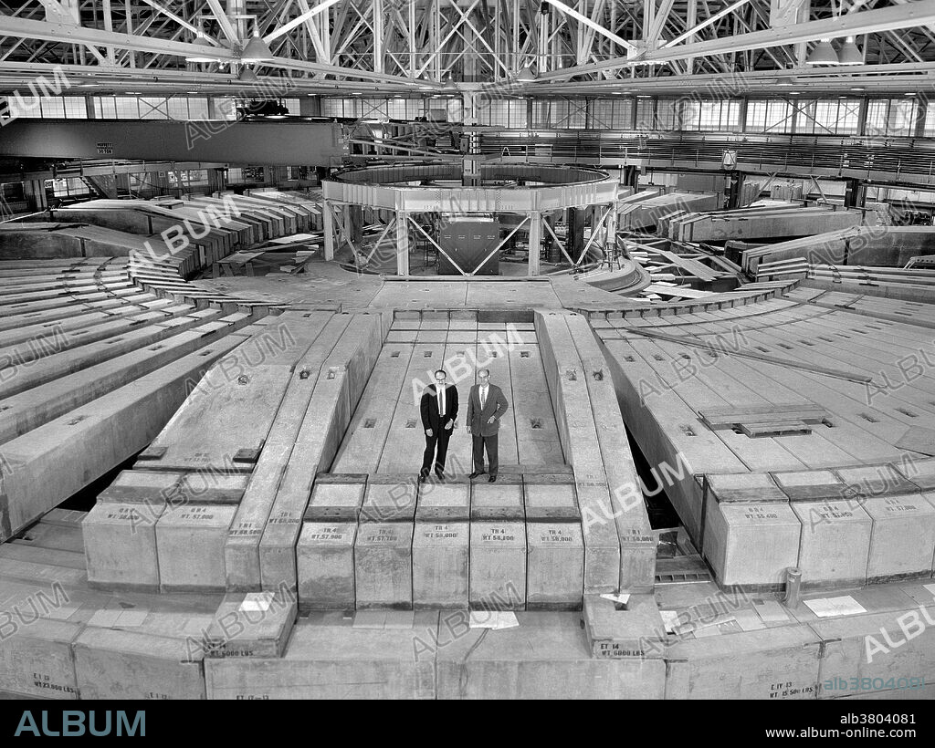 Wide-angle view of the remodeled Bevatron shows extensive new shielding, including seven-foot-thick concrete roof and "igloo" at hub. Taking in the view from the top are Lawrence Radiation Laboratory Director Edwin McMillan (left) and Bevatron Group Leader Edwin Lofgren. The Bevatron was a particle accelerator (specifically, a weak-focusing proton synchrotron) at Lawrence Berkeley National Laboratory, which began operating in 1954. The antiproton was discovered there in 1955, resulting in the 1959 Nobel Prize in physics for Emilio SegrÃ¨ and Owen Chamberlain. Edwin Mattison McMillan (September 18, 1907 - September 7, 1991) was an American physicist and Nobel laureate credited with being the first ever to produce a transuranium element. He shared the Nobel Prize in Chemistry with Glenn Seaborg in 1951. Edward Joseph Lofgren (born January 18, 1914) was an American physicist in the early days of nuclear physics and elementary particle research at the Lawrence Berkeley Laboratory (LBL). He was born in Chicago. He was an important figure in the breakthroughs that followed the creation of the Bevatron, of which he was the director for a time. He remained at the Laboratory until his retirement in 1982. He turned 100 in January 2014.