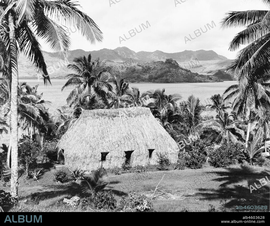 Fiji, A traditional Fijian 'bure'A traditional Fijian 'bure' (dwelling) sits amongst palm trees at the bottom of a slope, overlooking a coastal bay. Bures such as this usually consist of a wooden frame, which is completed covered with woven leaves and thatch. Caption reads: Typical Fijian native dwelling or 'Bure', 1965. 2005/010/1/14/17.