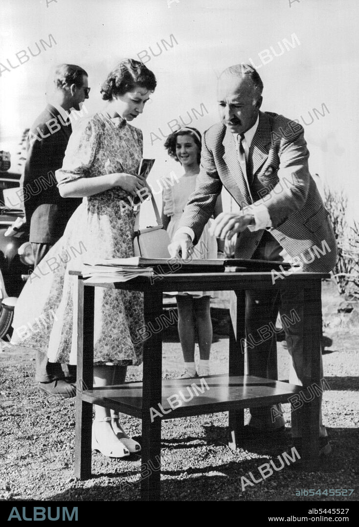 Start Park Tour -- Colonel Mervyn Cowie opens the visitors book for Princess Elizabeth and the Duke of Edinburgh to sign as they arrive at Nairobi National park, February 2, to start a car tour. The Royal tourist saw much of the wild life of the Presentation, including a lion, some 10 yards from the car devouring his kill. Colonel Cowie is Directors of the National Parks. His Daughter, Mitzie, smiles in the background as the Duke chats with her. February 06, 1952. (Photo by Associated Press Photo).