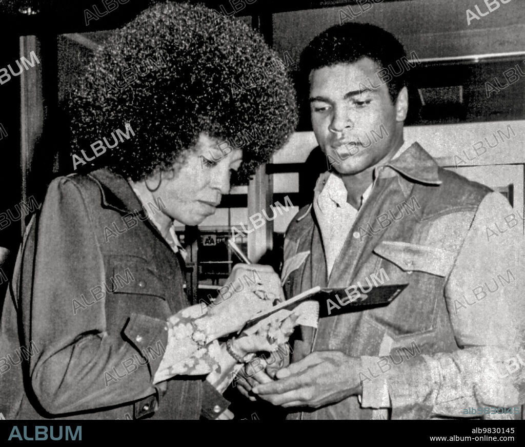 New York, New York September 9, 1974, Muhammad Ali and Angela Davis exchange autographs when they run into each other at La Guardia Airport. Ali was on his way to Zaire to fight George Foreman,.