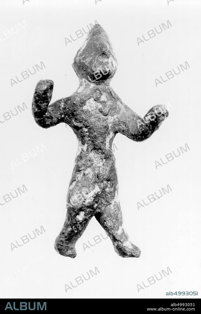 A bronze, roughly modeled figure of a walking man. Left leg forward, right leg backward. The arms are half raised, the left forward, the right side. The right hand is pierced. Left hand is missing. The head is facing down and wears a pointed hat. The figure belongs in the group 'Canaanitic metal figurines', figurine, metal, bronze, H 6.4 cm, Iron Age I 1200-1100 BC, Israel ?, Syria?.