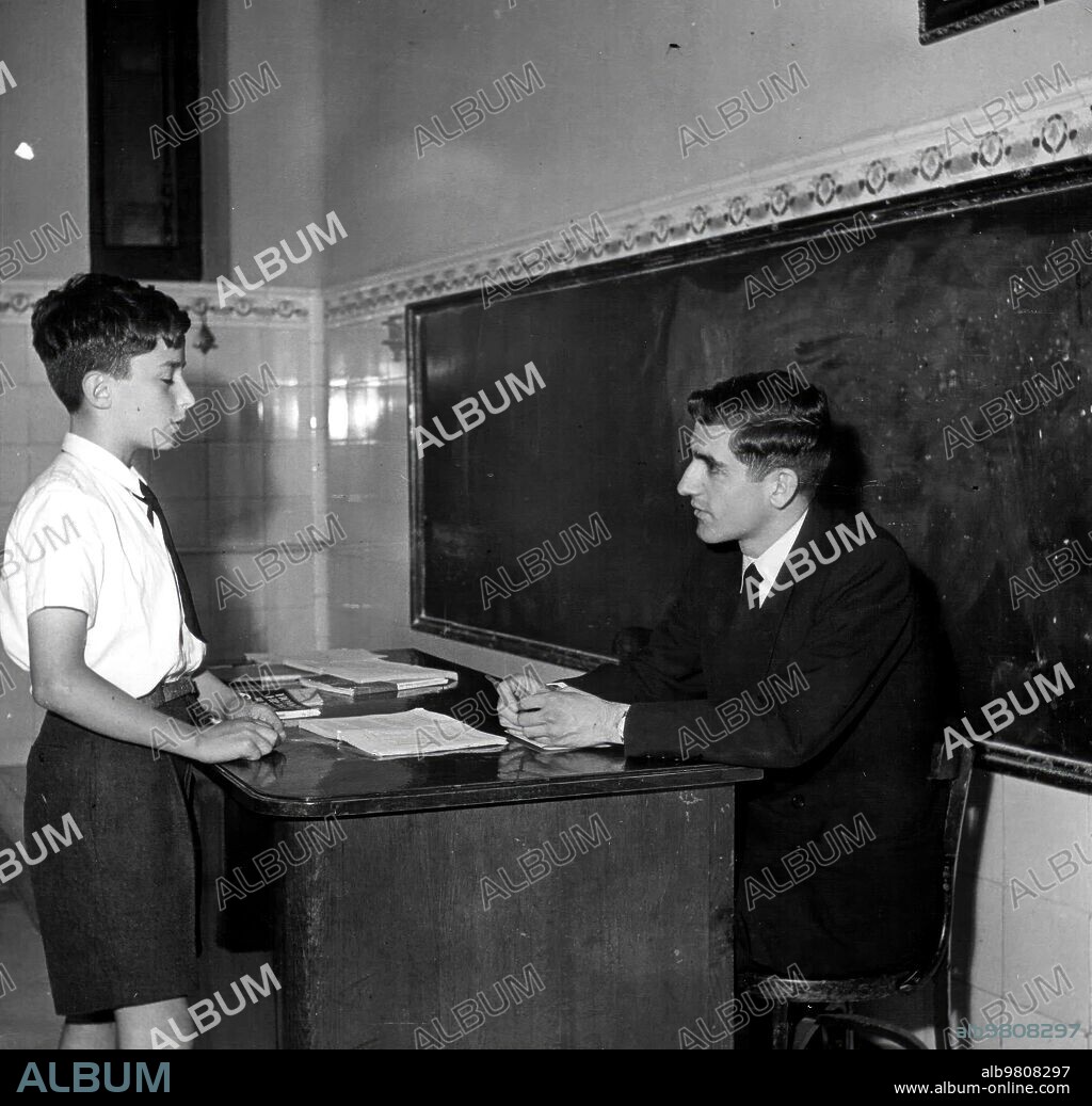 October 1958. A teacher asking the lesson to his student.