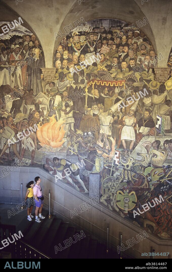 Visitors look at a Diego Rivera mural at the National Palace in Mexico City, Mexico.