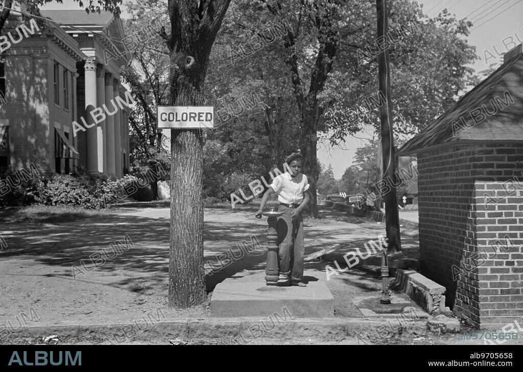 Boy at Drinking Fountain with Sign "Colored" on County Courthouse Lawn, Halifax, North Carolina, USA, John Vachon, Farm Security Administration, April 1938.