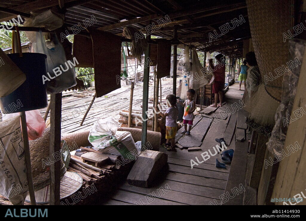 Iban tribal villagers sheltering from the rain on their longhouse verandah, Lemanak River, Sarawak, Malaysian Borneo, Malaysia, Southeast Asia, Asia.