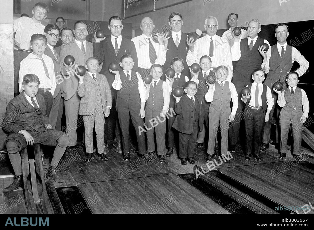 Entitled: "Singer's Midgets Bowling at YMCA." Singer's Midgets were a popular vaudeville group in the first half of the 20th century. Leopold von Singer (May 3, 1877 - March 5, 1951) formed Singer's Midgets in 1912-13, and built the Liliputstadt, a "midget city" at the "Venice in Vienna" amusement park, where they performed. The Liliputstadt was a major success, Singer began to tour with his performers throughout Europe and, in the process, recruited new members. After WWI broke out, the troupe traveled to the United States, and remained there for the remainder of their existence where they performed in vaudeville theaters. During the 1930s, some of Singer's Midgets began appearing in films, most notably, The Terror of Tiny Town and The Wizard of Oz. The Singer Midgets disbanded in the mid-1940s, with many members returning home to their native Europe. Photographed by National Photo Company, 1924.