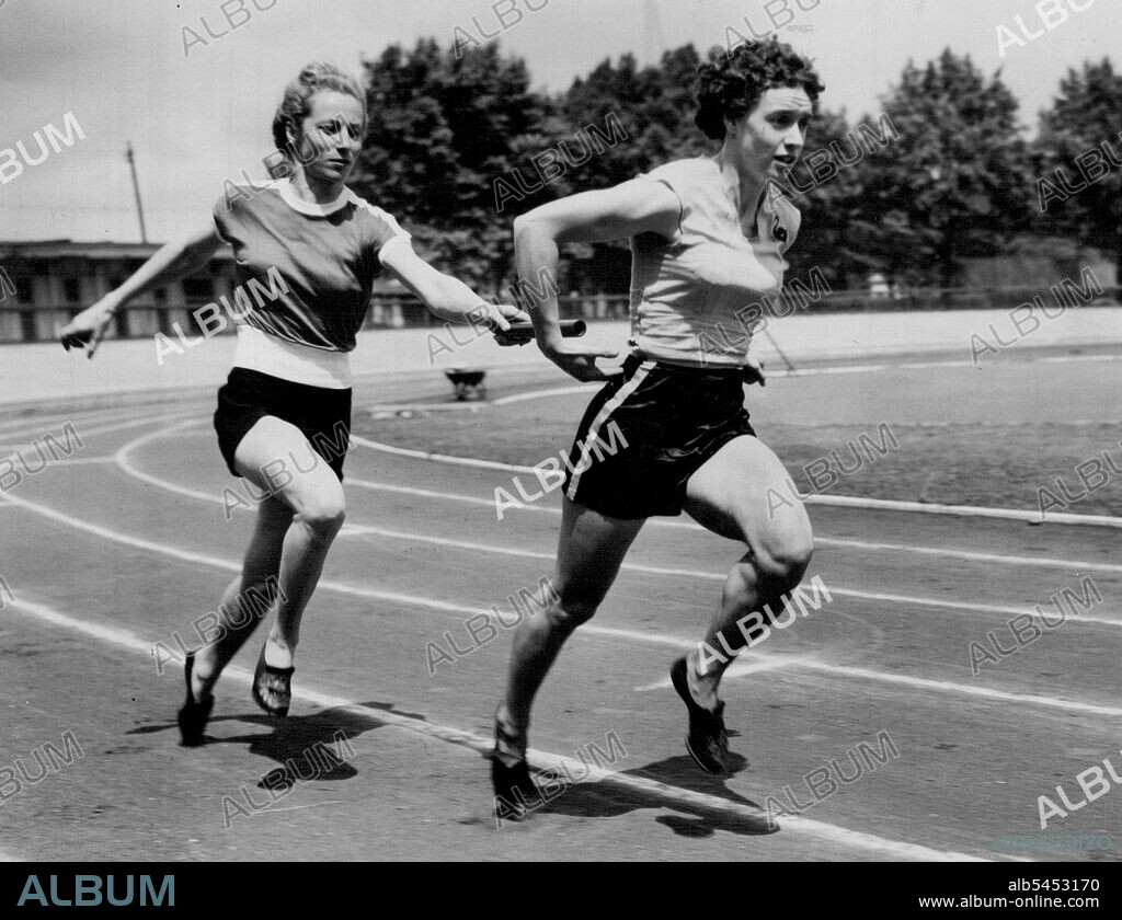 Olympic Girls From 'Down Under' Train At Paddington -- Australian sprinter and hurdler Shirley Strickland hands over to fellow-country woman Verna Johnston as they practice relay changeovers during a training spell with other Australian Olympic Games women athletes at Paddington Recreation Ground. June 19, 1952.
