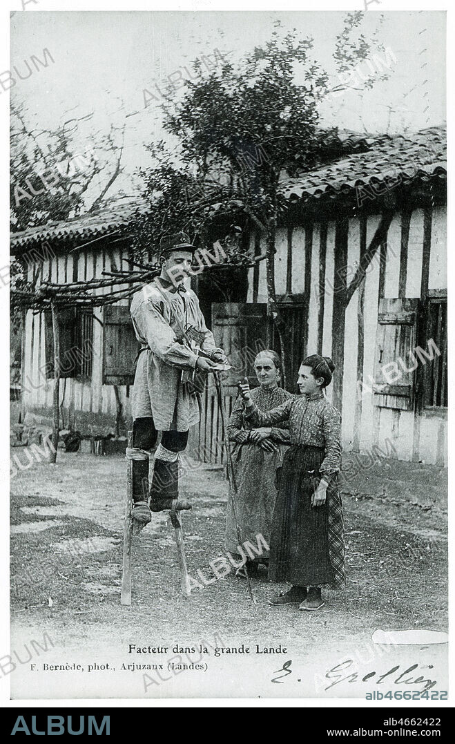 'Facteur dans la grande Lande. ' Un jeune facteur sur des echasses distribue le courrier a deux femmes. Carte postale vers 1900-1910, photographie anonyme. Credit Collection Kharbine Tapabor.
