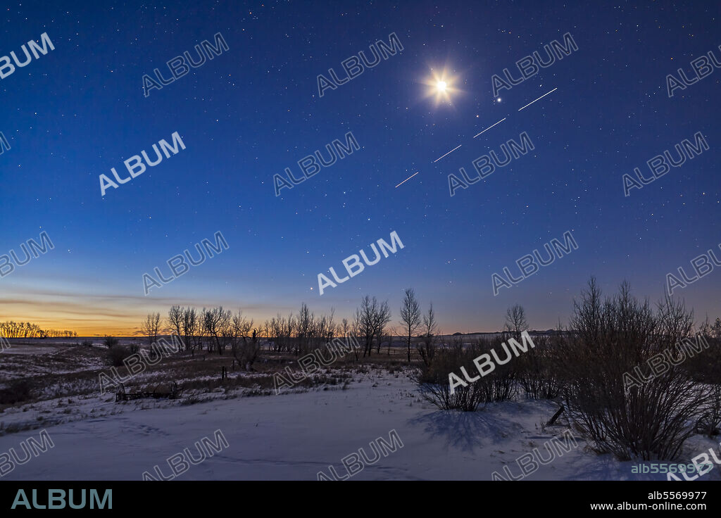 A busy morning sky, with the waning crescent Moon shining above the pairing of Mars (left) and Jupiter (right), with the Space Station also streaking by below in four exposures. The Moon and planets are in Libra. Left of centre, Antares and the stars of Scorpius are just rising in the dawn twilight.