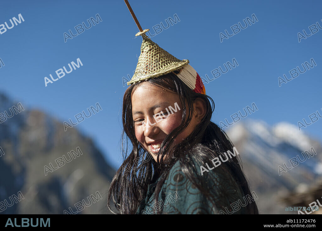 A Layap girl wearing a traditional hat smiles for the camera in the remote village of Laya, Bhutan, Asia.